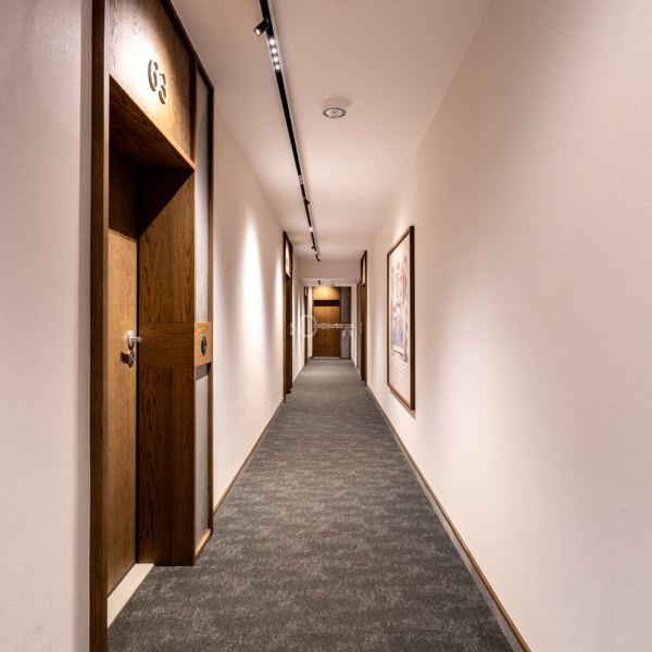 Safer, moderner Hotellflur mit Türen und Bildern, gepflegte Inneneinrichtung.