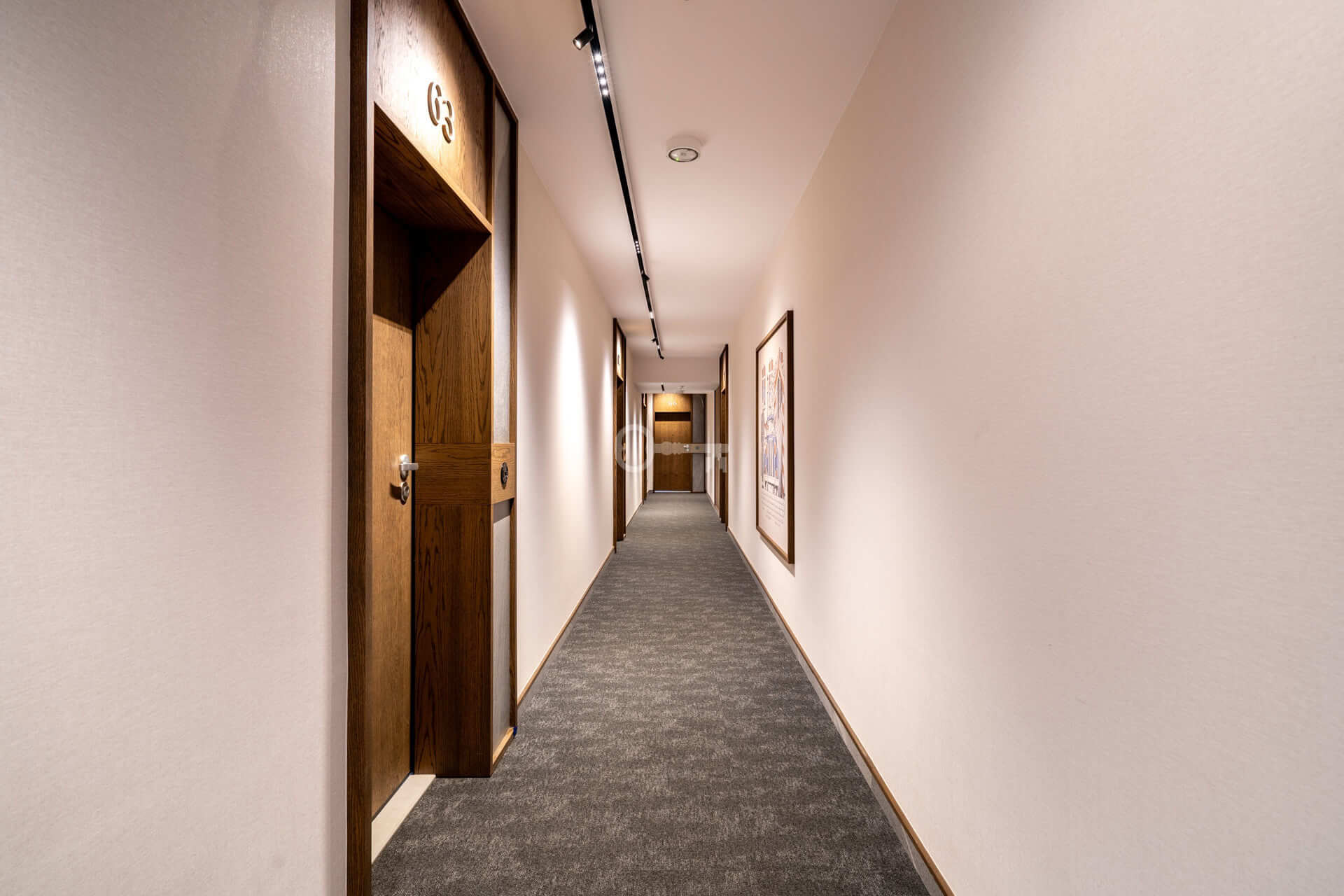 Safer, moderner Hotellflur mit Türen und Bildern, gepflegte Inneneinrichtung.